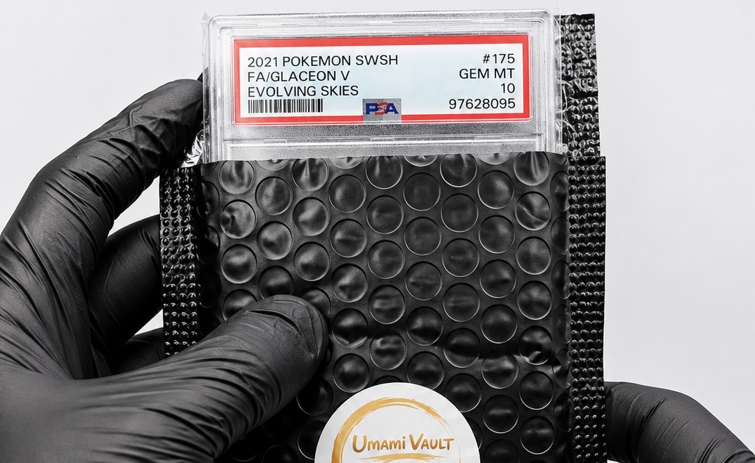 Umami Vault specialist in black nitrile gloves holding a PSA 10 graded Glaceon V card above a bubble-wrapped, branded package ready for shipment